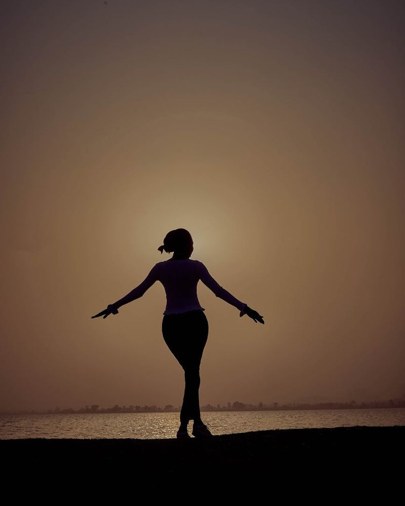 A woman in a peaceful yoga pose against a dark background, representing evening practice.